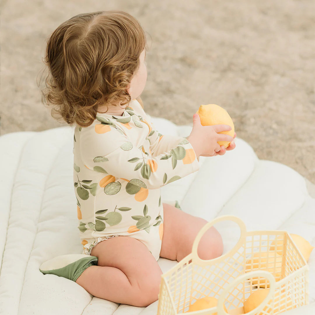 Back view of baby girl citrus long-sleeve rashguard swimsuit showing zipper and snap details.