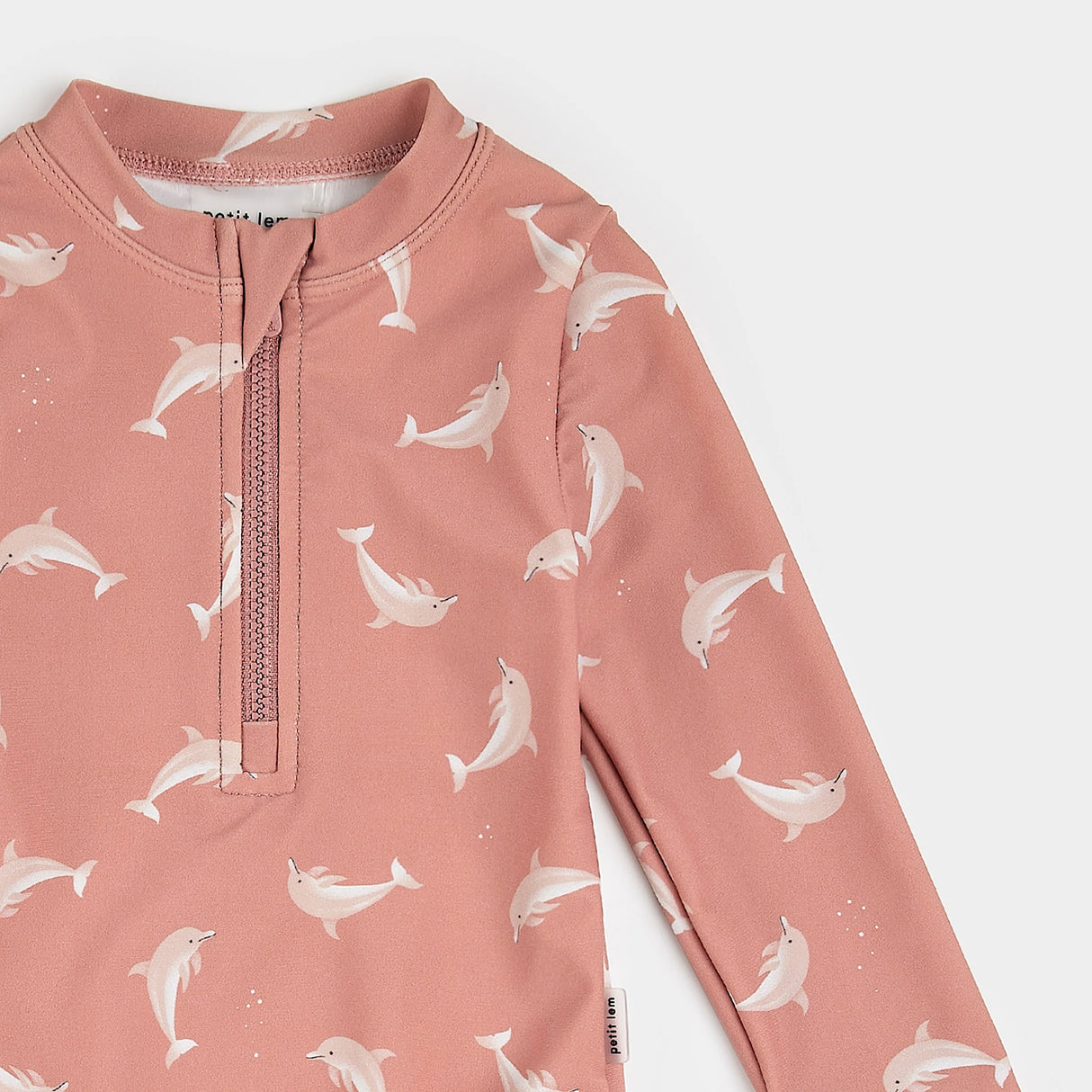 Close-up of Wild Rose Petit Lem long-sleeve swimsuit with white dolphin print and frilled leg openings