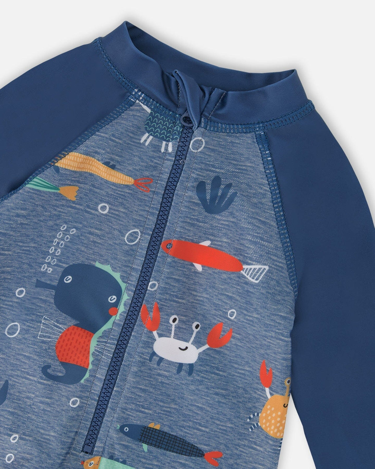 Close-up of zipper, neckline, and marine animals pattern on blue rashguard swimsuit for boys
