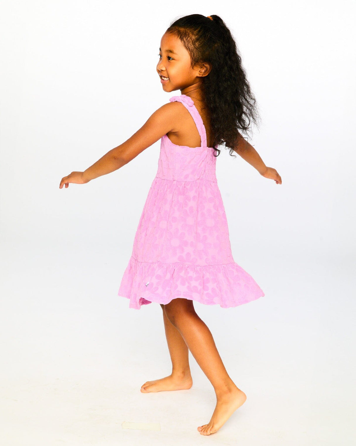 Girl twirling in pink flower cover-up dress showing movement of tiered skirt