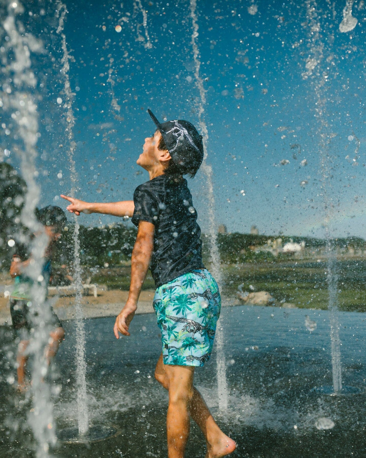 Boy running through water wearing blue skeleton print boys swim trunks