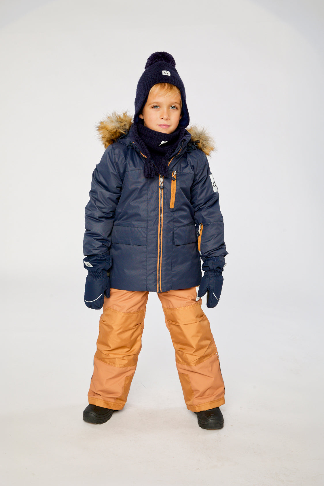 Child wearing the Deux par Deux PLAY two-piece snowsuit in Navy Blue with Brown Pants in a winter lookbook view