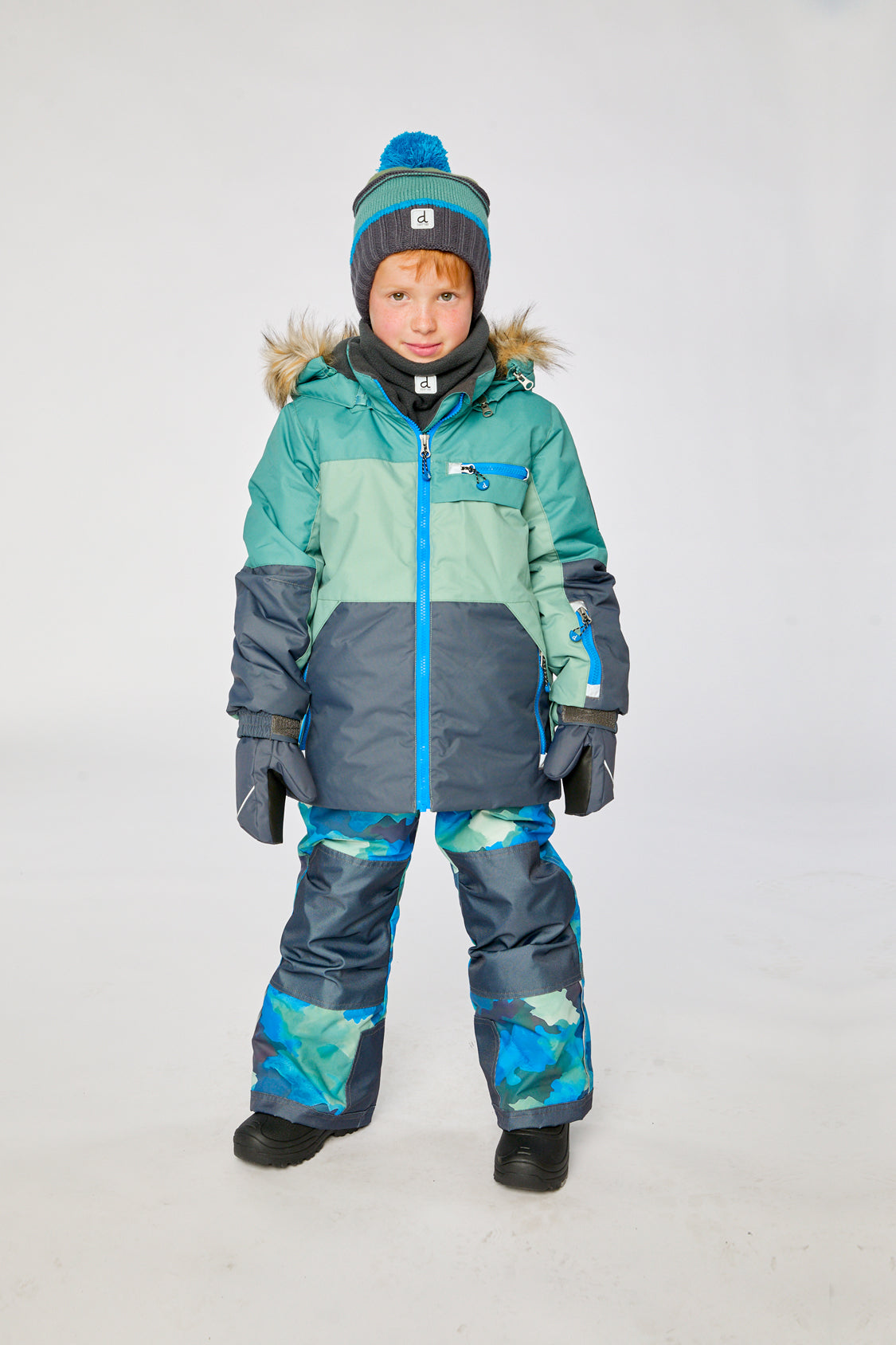 Boy wearing Deux par Deux green navy colorblock PLAY snowsuit with blue camo snow pants