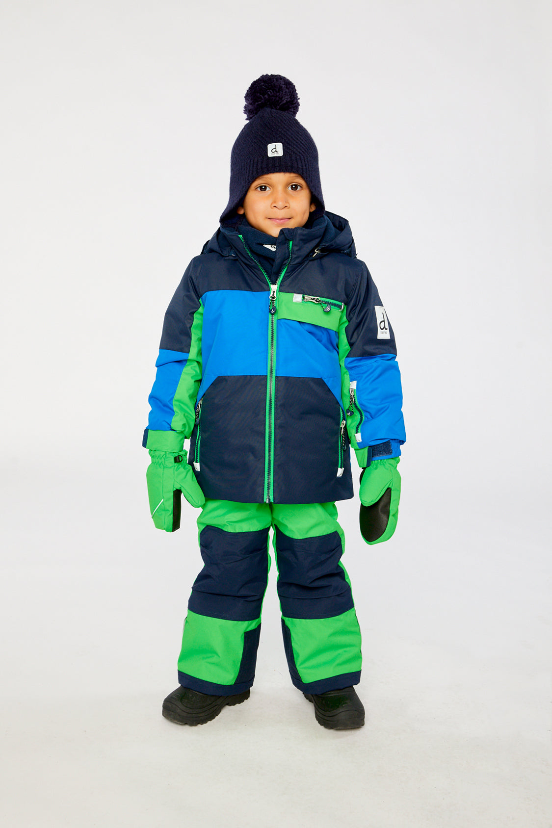 Child wearing the Deux par Deux PLAY two-piece snowsuit in Royal Blue and Green Colorblock in a winter lookbook view