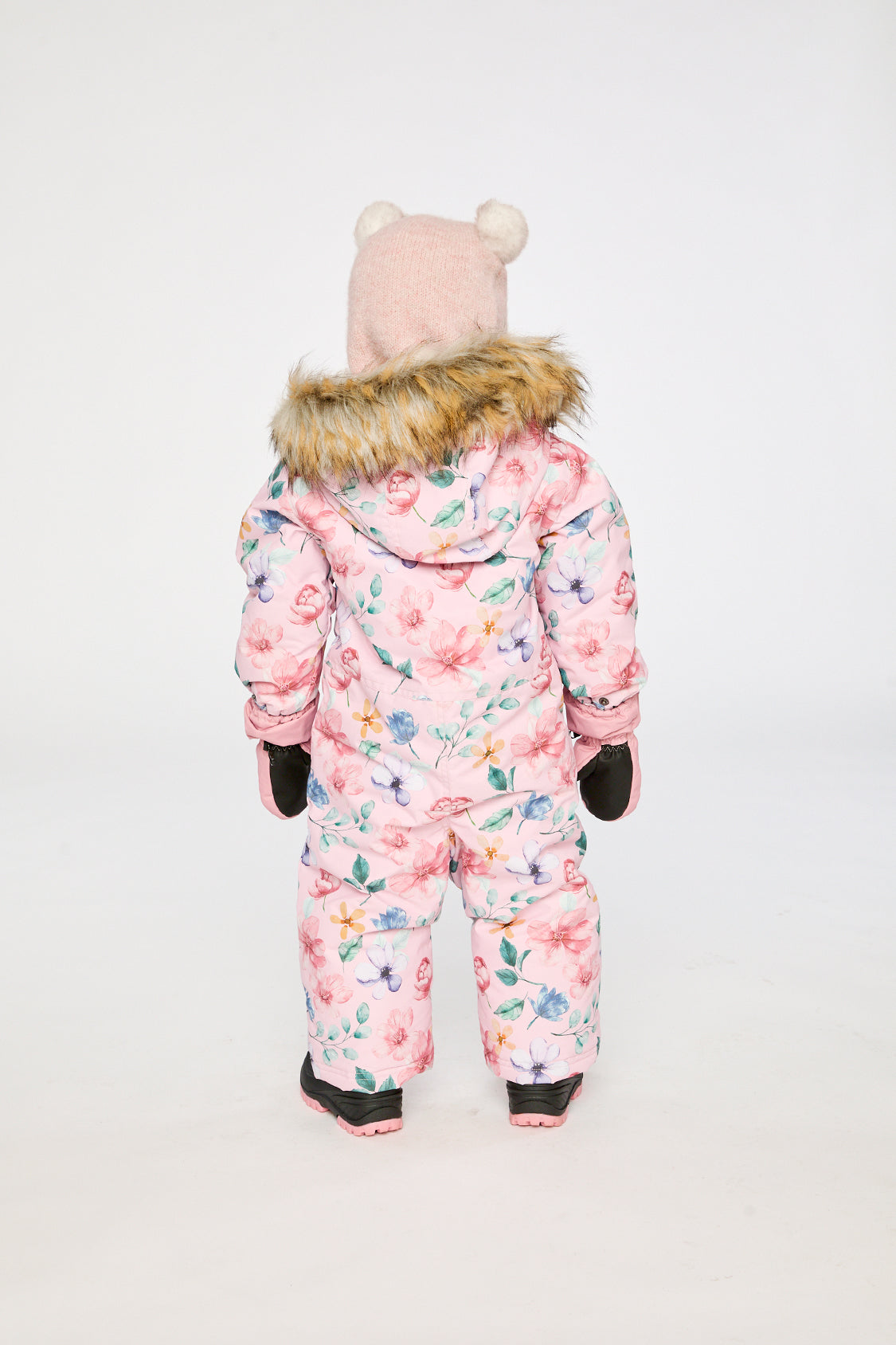 Back view of a toddler girl in the pink floral print snowsuit with faux-fur trimmed hood