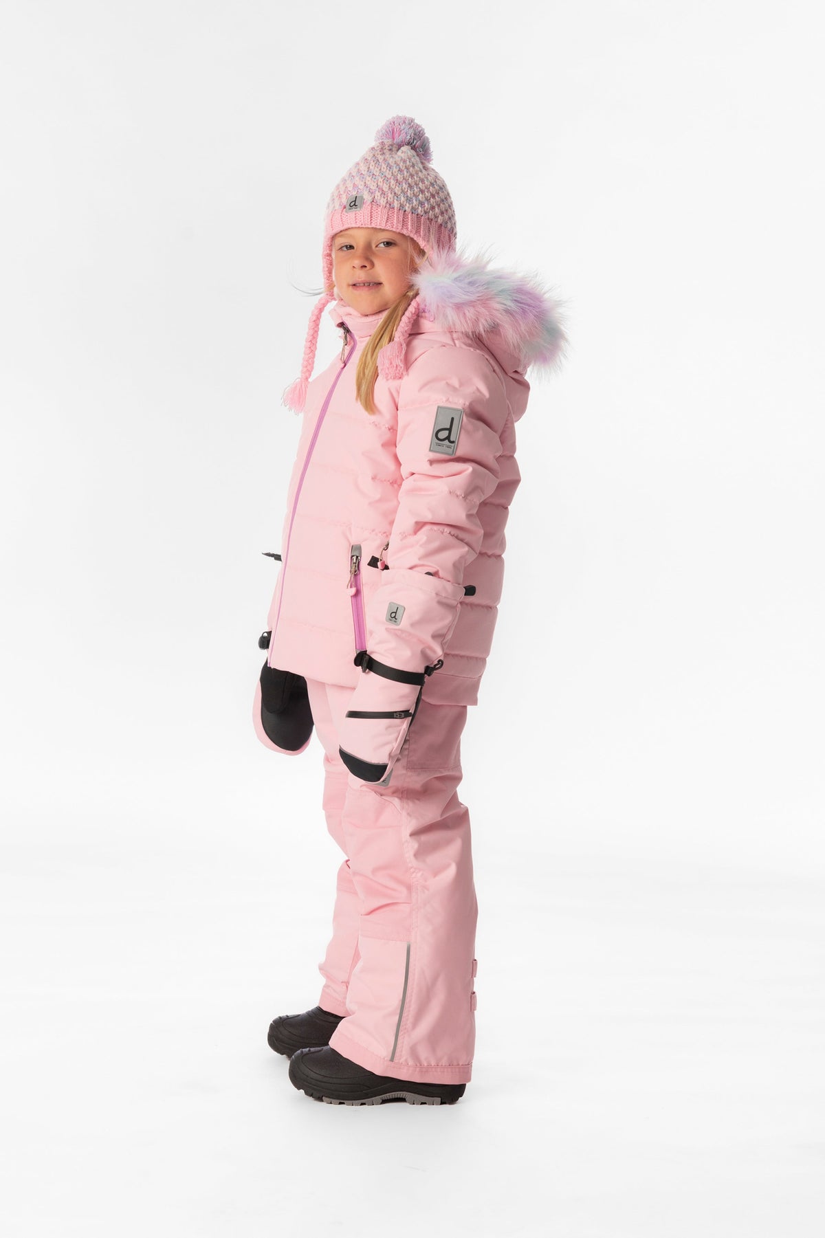 Girl in the light pink Deux par Deux PLAY snowsuit, side view