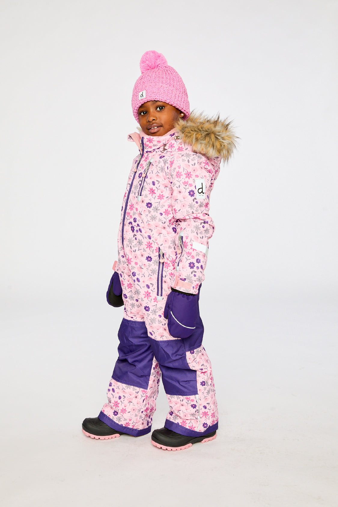 Deux par Deux kids PLAY one-piece snowsuit in Pink Mini Flower Print shown from an alternate modeled winter angle