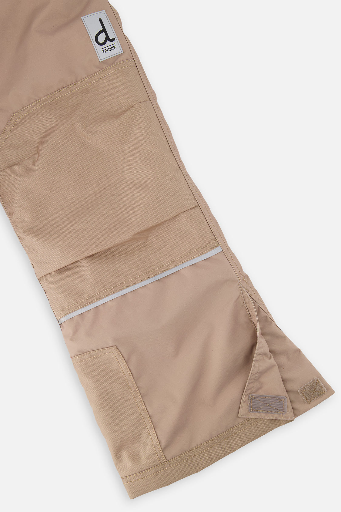 Close-up of the taupe snow pants leg with reinforced panels and inner snow gaiter