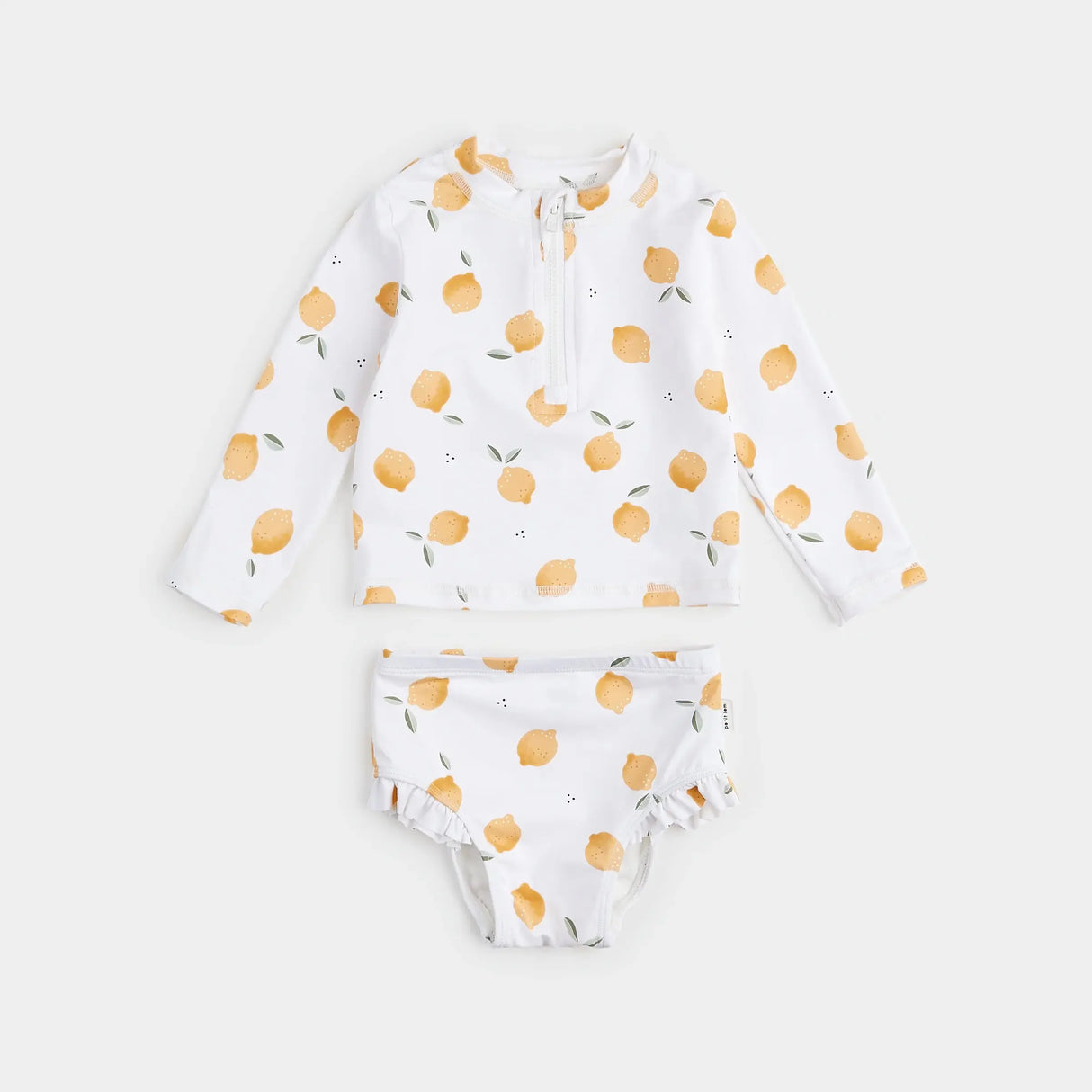 Lemon-print long-sleeve rashguard set with high-waisted swim pants laid flat, baby rashguard set on antique white background.