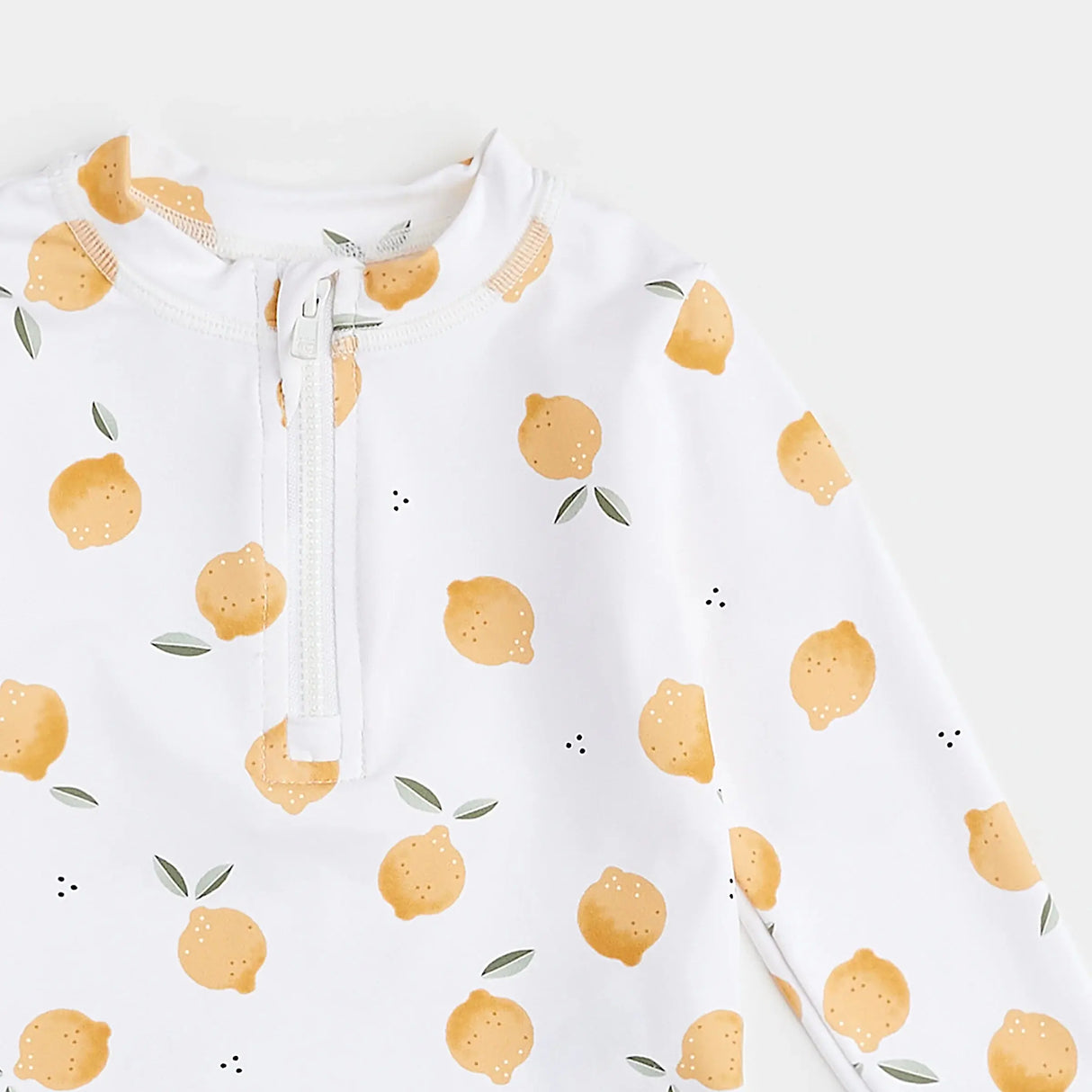Close-up of lemon-print rashguard top showing front zipper and citrus pattern.