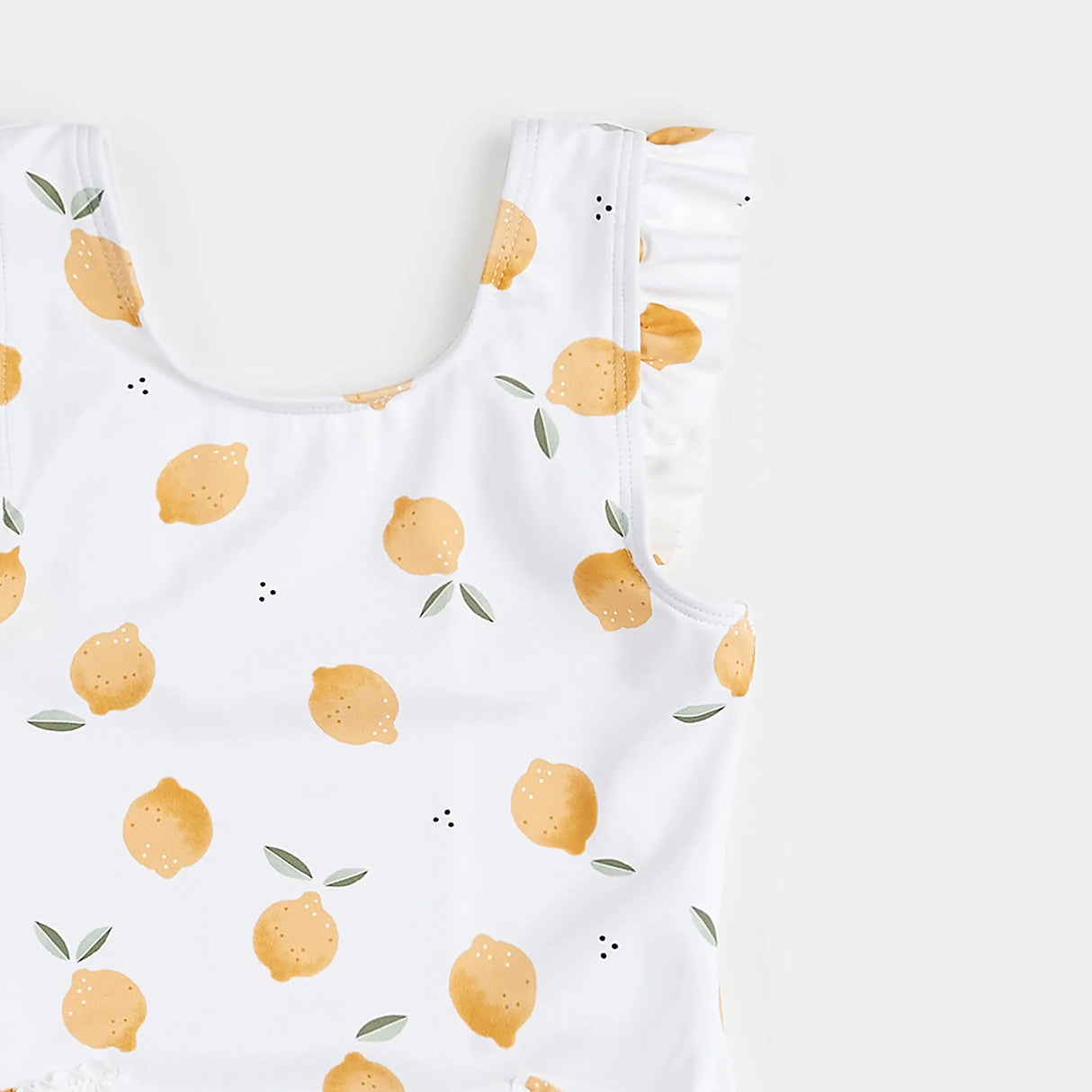 Close-up of lemon-print swimsuit neckline showing flutter straps and citrus pattern.