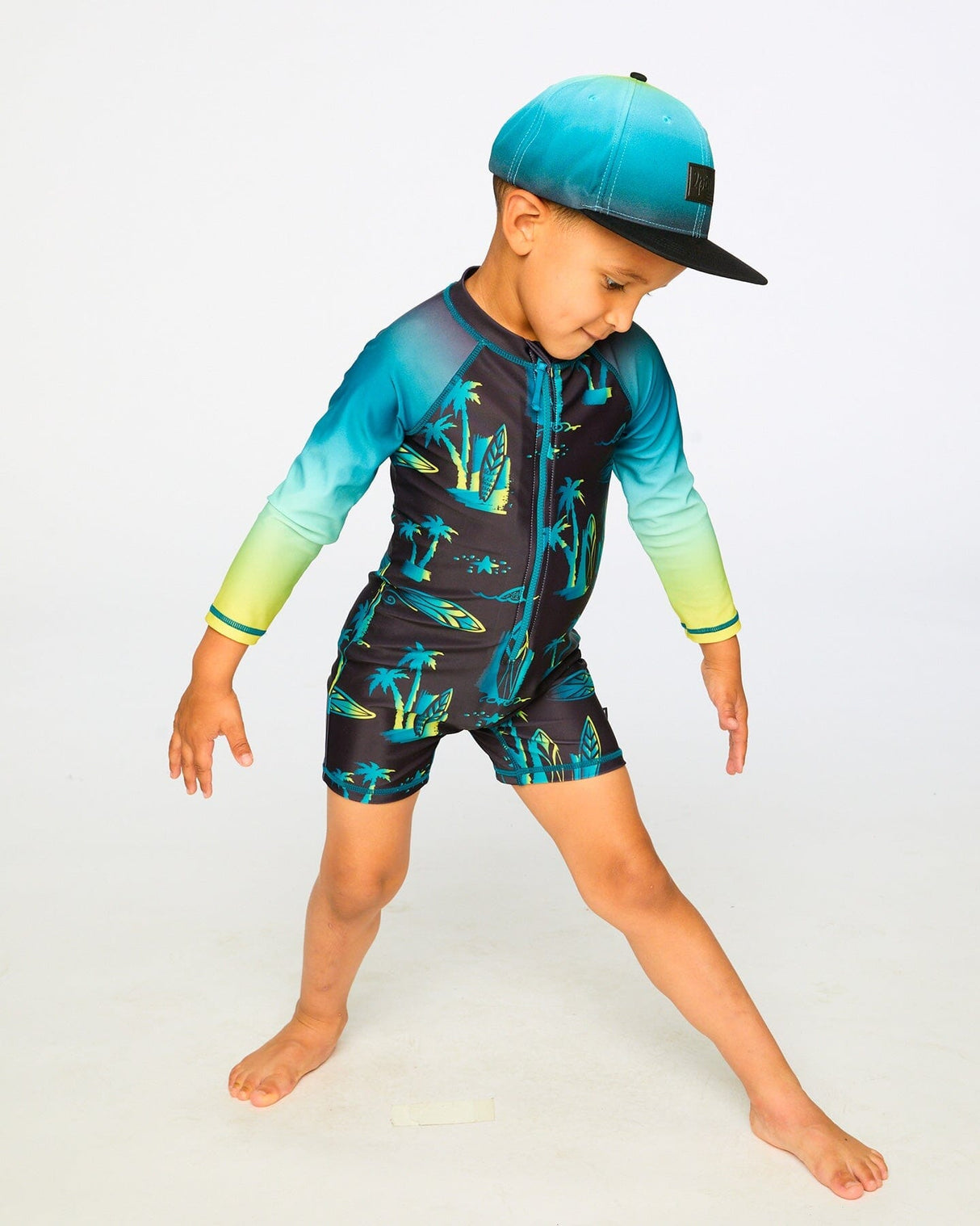 Boy posing in studio in black surf long sleeve rashguard romper front view