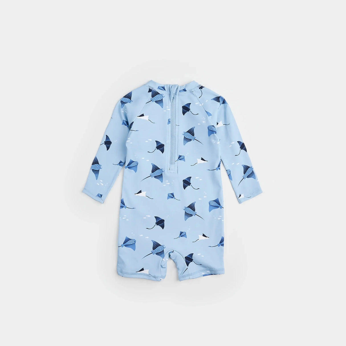 Baby girl wearing sky blue stingray print long-sleeve swim romper by Petit Lem at the beach