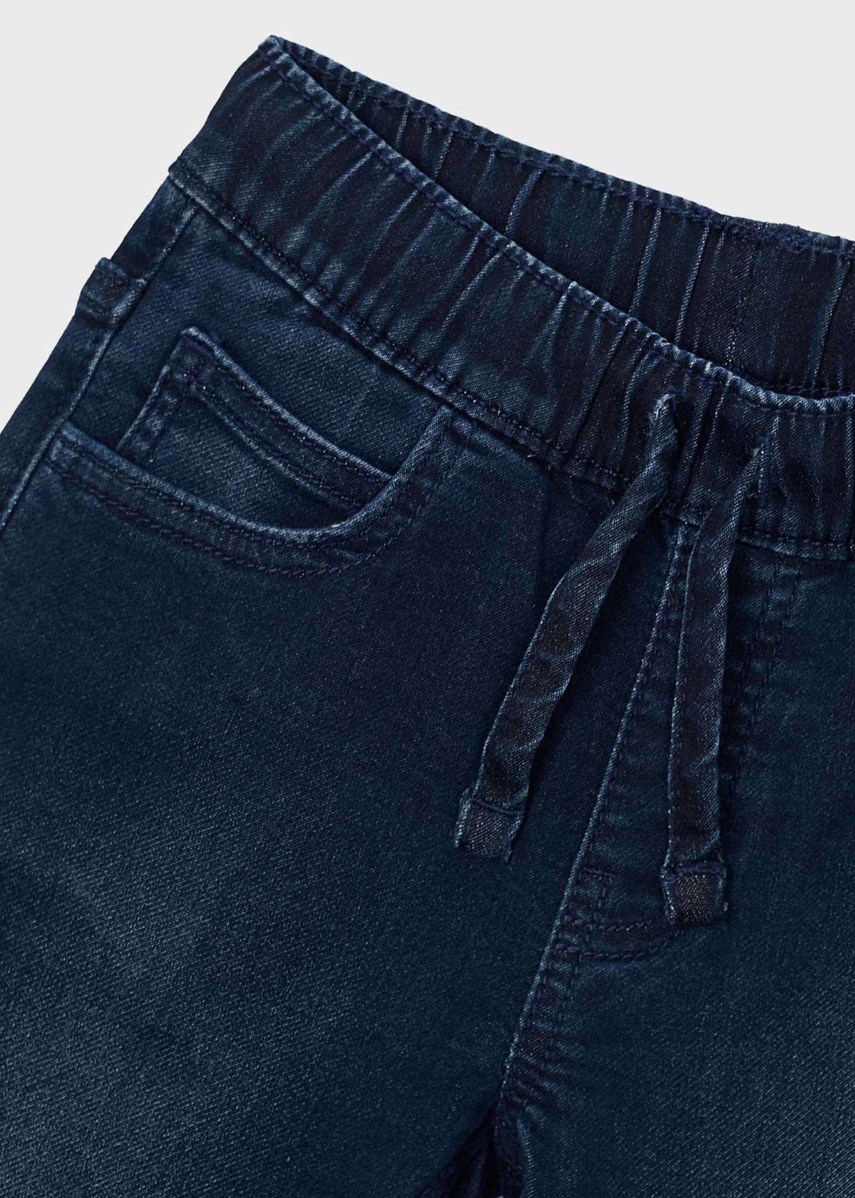 Close-up of elastic drawstring waist and front pocket on dark blue jeans
