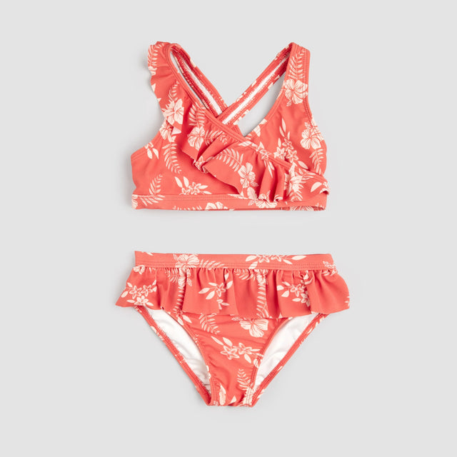 Raspberry hibiscus Petit Lem two-piece swimsuit set flat lay showing ruffled cross-over bikini top and bottoms.