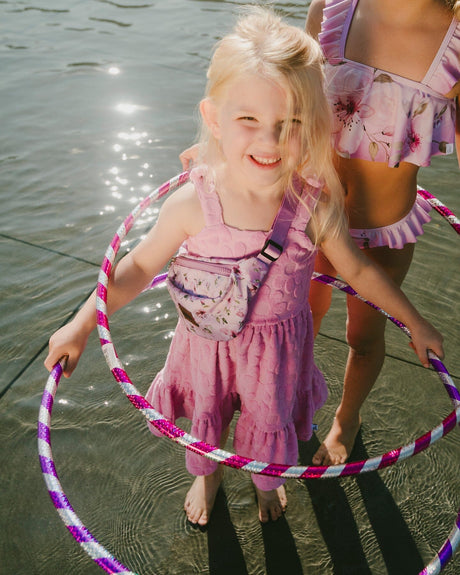 Girl standing in water wearing pink beach cover-up dress over swimsuit holding a hoop