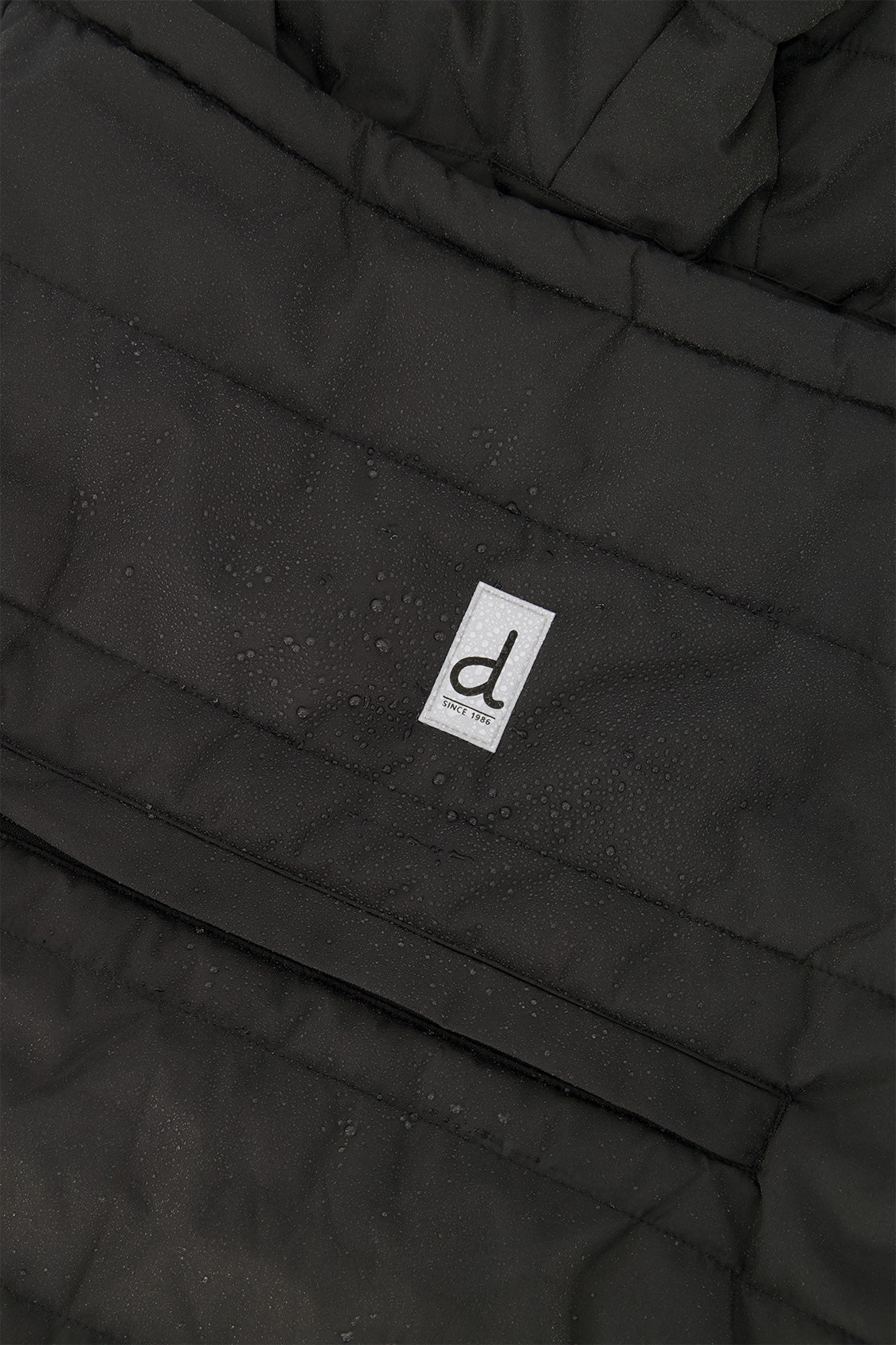 Close-up of the black quilted shell, zip pocket and logo tab