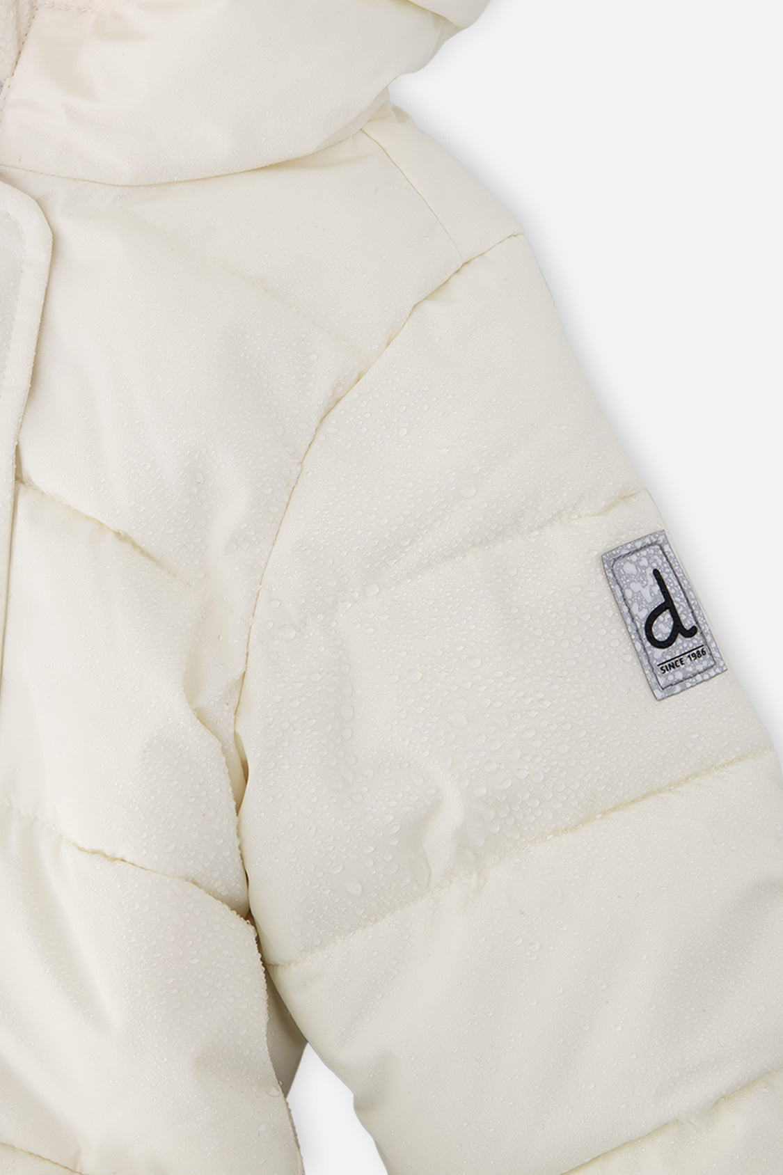 Close-up of the off-white quilted sleeve with Deux par Deux logo patch