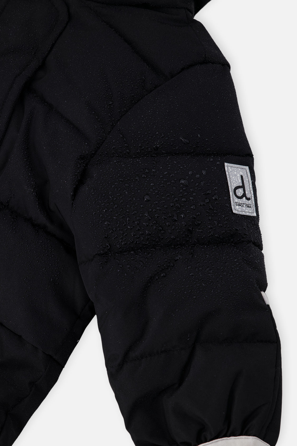Close-up of the black quilted sleeve with Deux par Deux logo patch