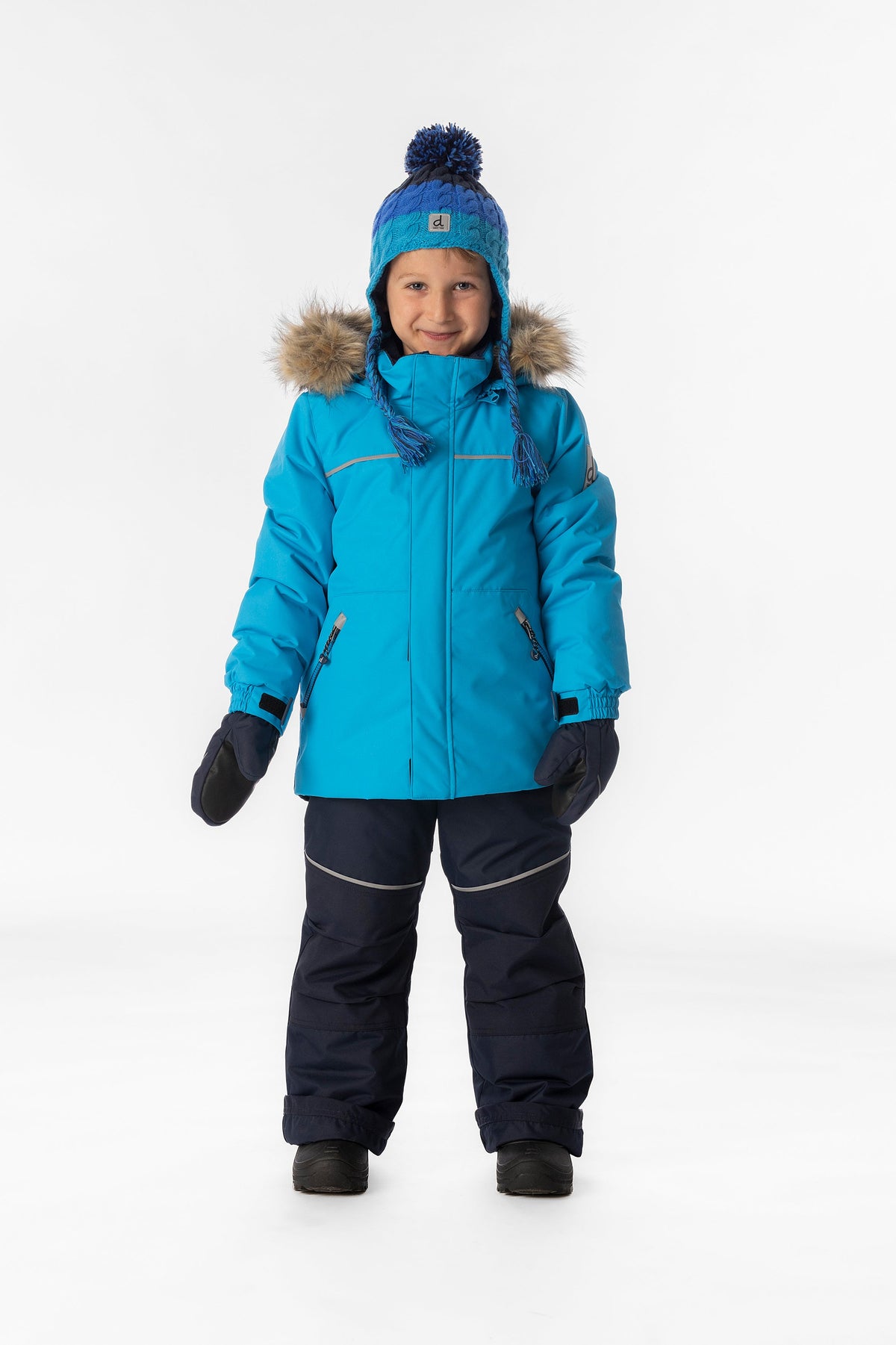 Boy standing in the bright blue and navy Deux par Deux DISCOVER snowsuit, full-length front view