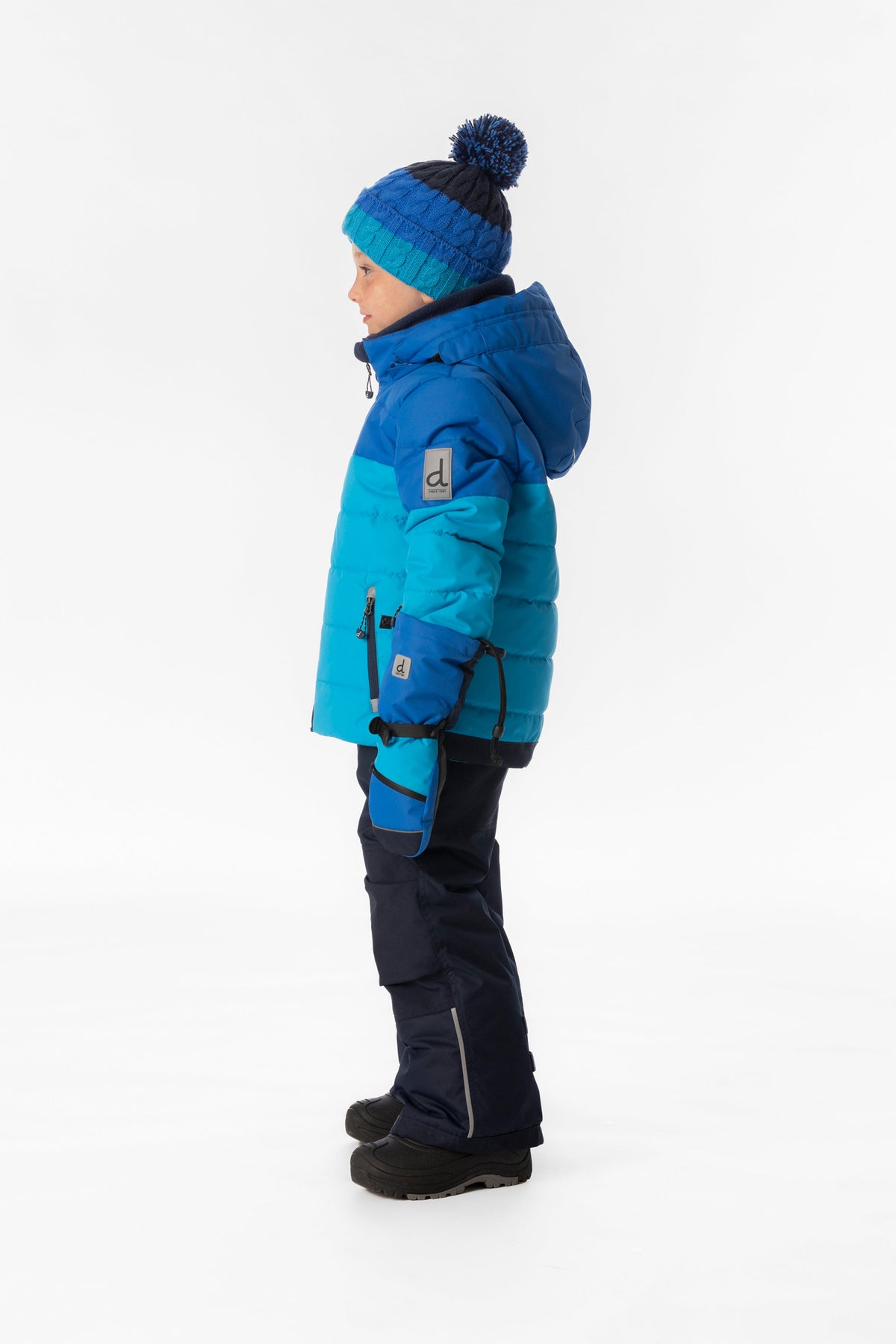 Boy in the light and dark blue Deux par Deux PLAY snowsuit, side view