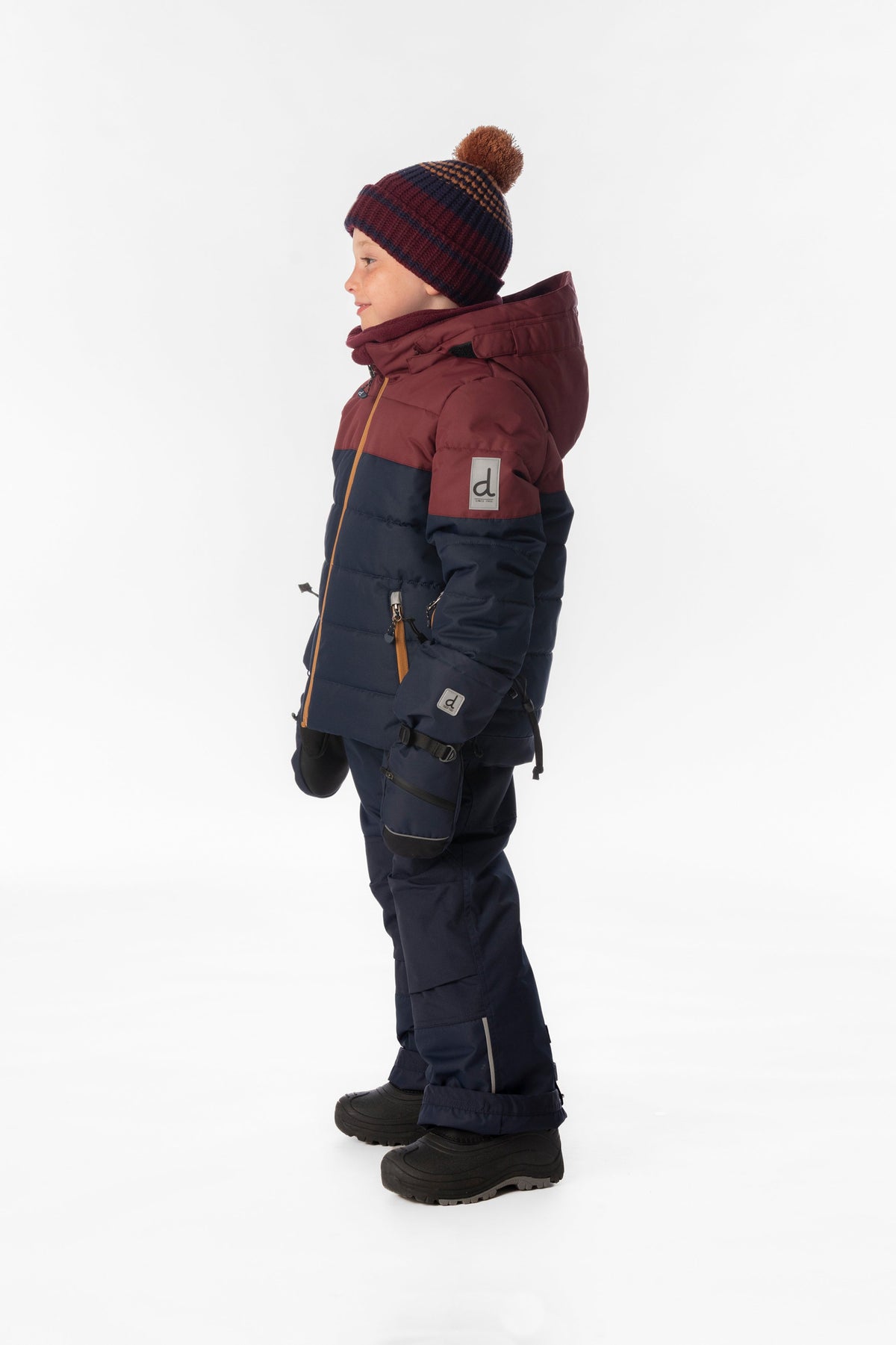 Boy in the navy and burgundy Deux par Deux PLAY snowsuit, side view
