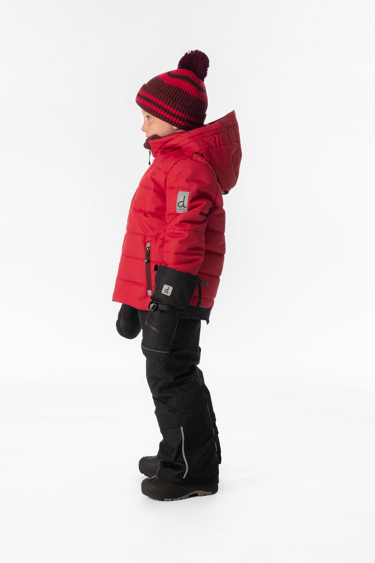 Boy in the red and black Deux par Deux PLAY snowsuit, side view