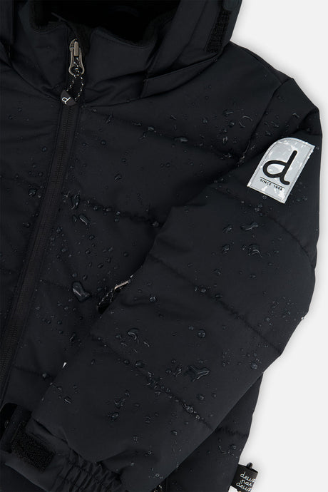 Deux par Deux boys PLAY snowsuit, all-black – close-up of the water-repellent jacket shell and logo patch