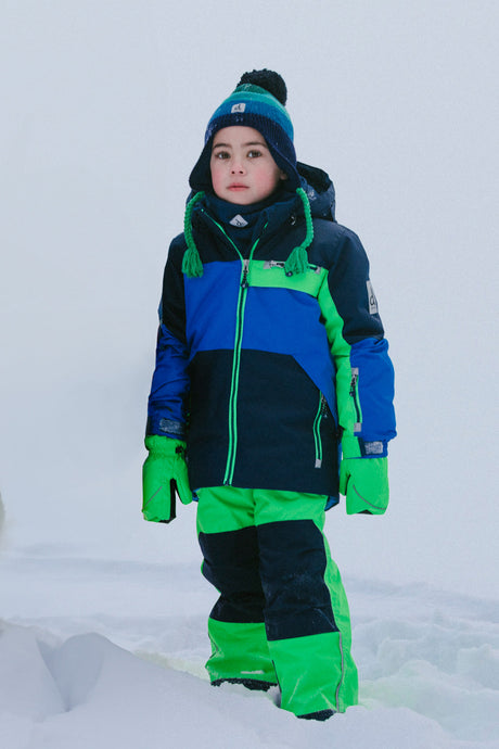 Child wearing the Deux par Deux PLAY two-piece snowsuit in Royal Blue and Green Colorblock during outdoor winter play