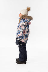 Side view of a girl wearing the watercolor flower PLAY jacket and navy snow pants