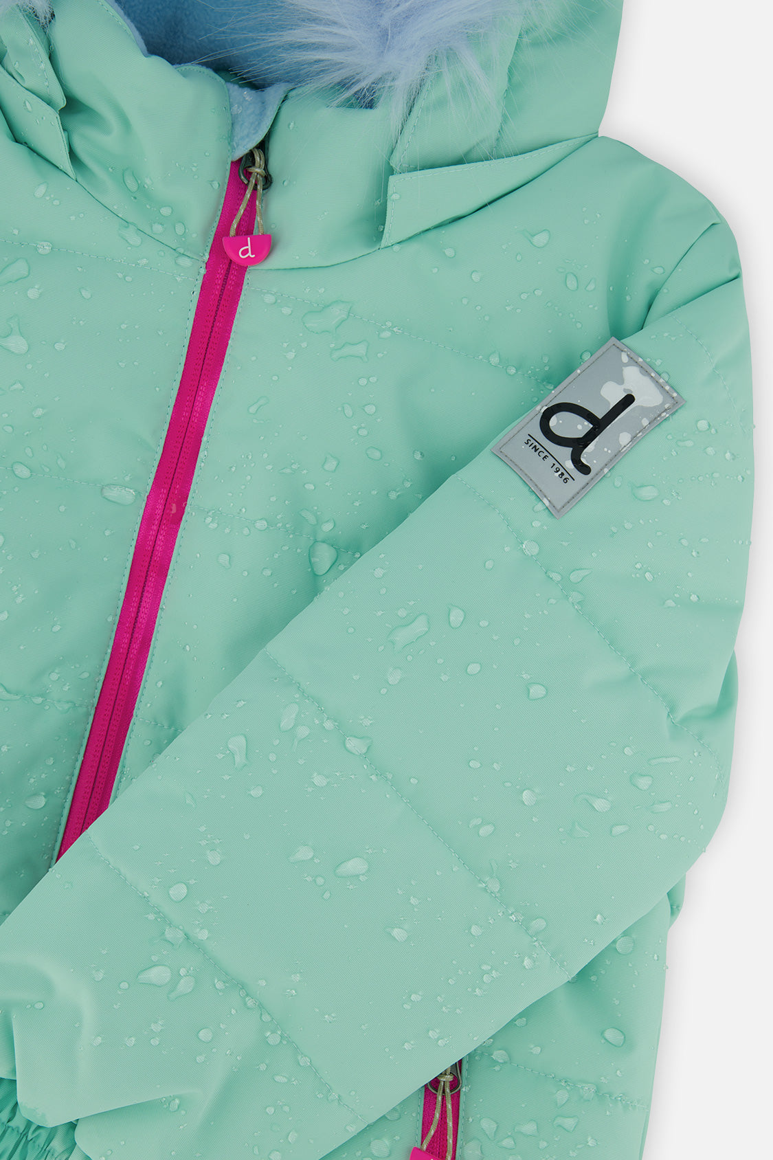 Deux par Deux girls PLAY snowsuit, mint green and light blue – close-up of the water-repellent jacket shell and logo patch