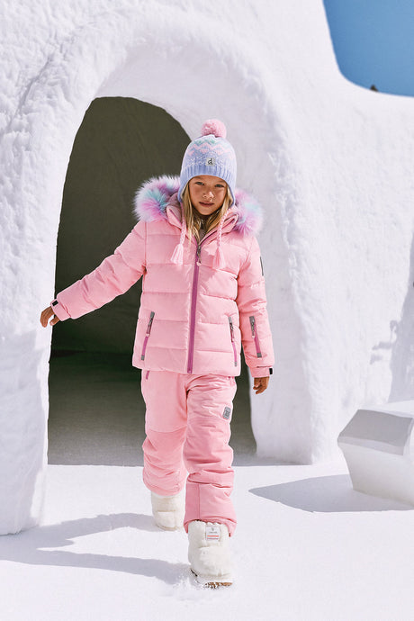Girl walking out of a snow igloo in the light pink Deux par Deux PLAY snowsuit