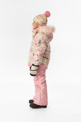 Side view of a girl wearing the pink mini flower PLAY jacket and pink snow pants
