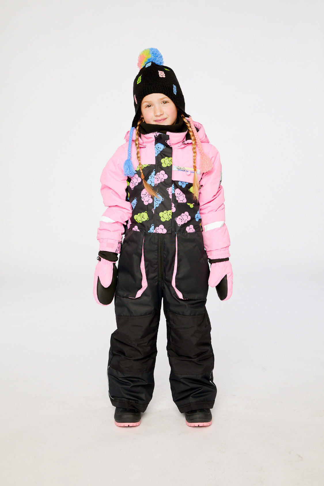 Child wearing the pink and black gummy bear Deux par Deux PLAY snowsuit in a winter lookbook view