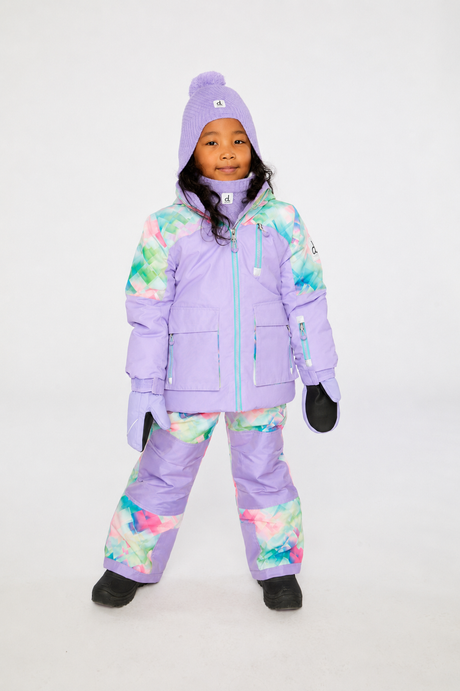 Front view of a child wearing the Deux par Deux lavender jacket and diamond-print snow pants with lavender knee panels
