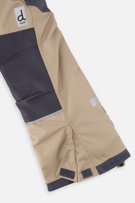 Close-up of the taupe and grey snow pants leg with reinforced panels and inner snow gaiter