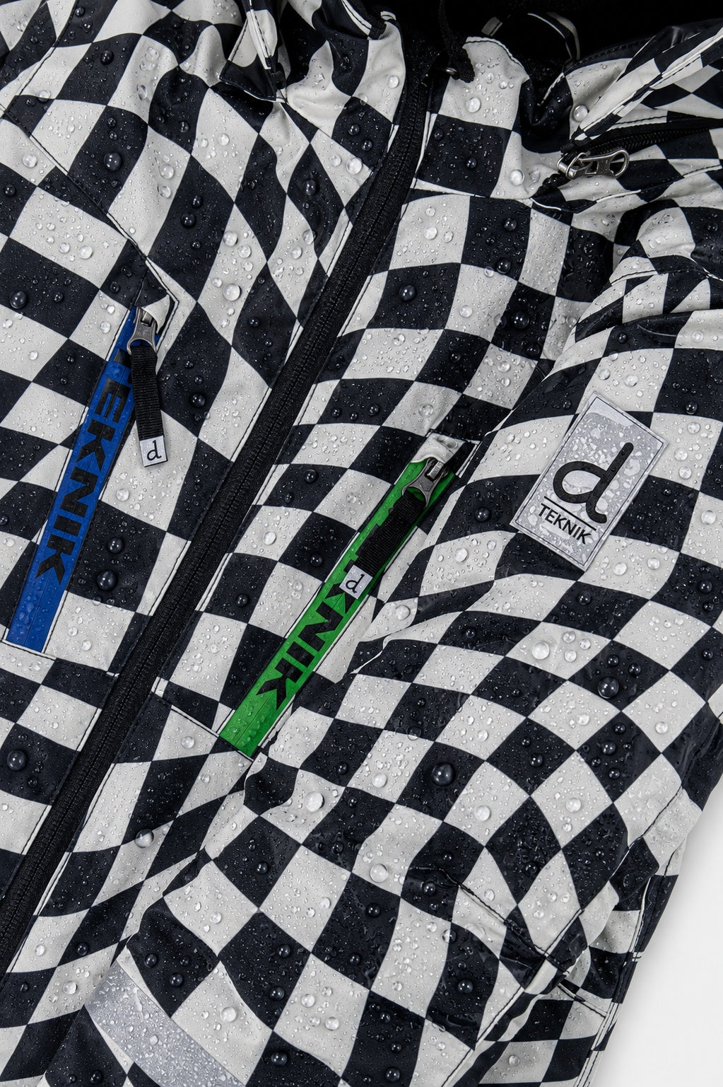 Close-up of the checkered print, chest zipper and logo on the TEKNIK jacket