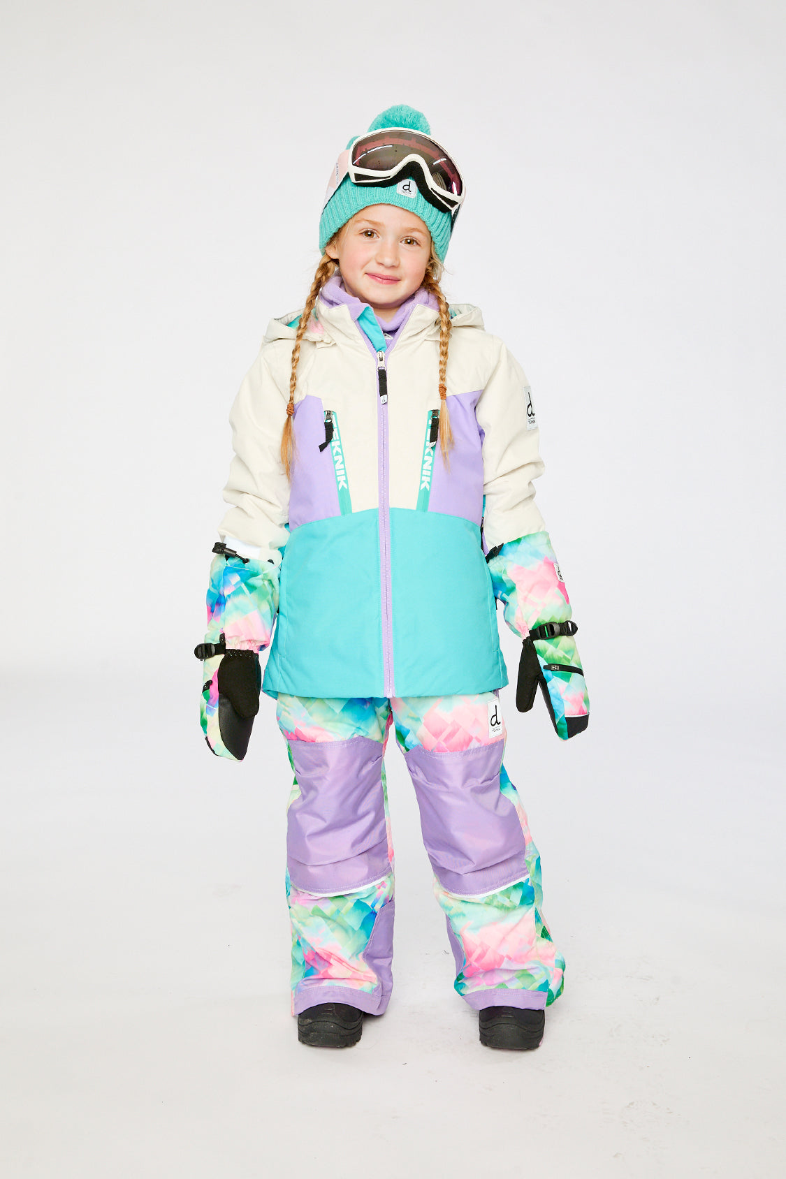 Child wearing the Deux par Deux TEKNIK two-piece snowsuit in Multicolored with A Diamond Pattern in a winter lookbook view