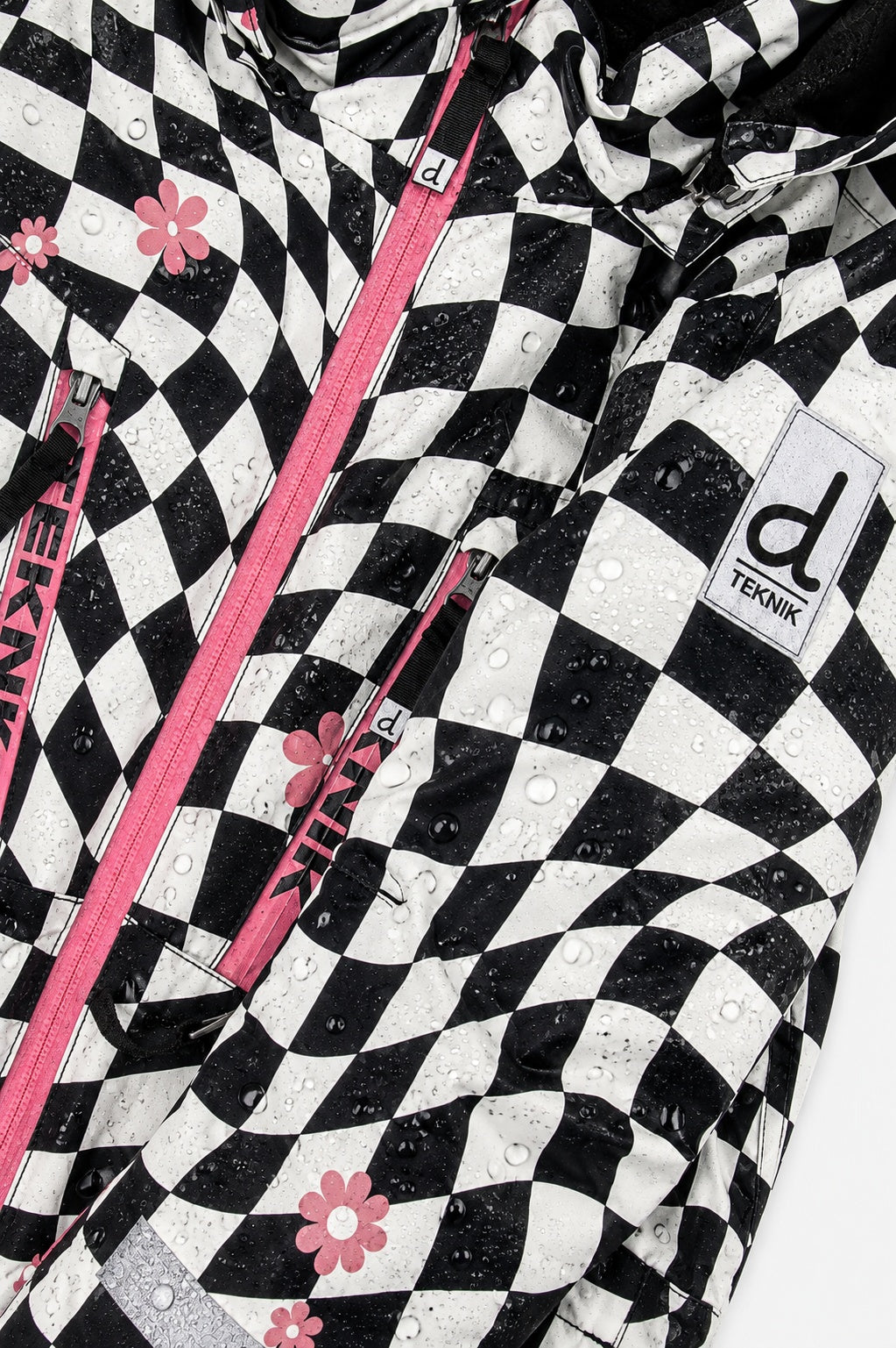 Water beading on the checkered TEKNIK jacket shell beside the logo patch
