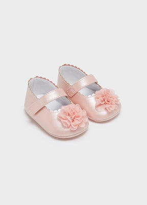 Blush pink newborn girl shoes with flower appliqués, angled pair view