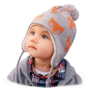 Toddler wearing a grey fox-pattern knit ear-flap hat, front portrait