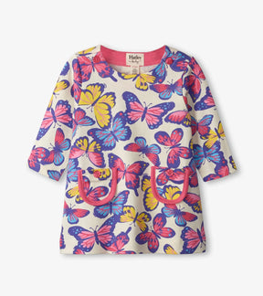 Front of Hatley Kaleidoscope Butterflies cream dress with colorful butterflies, pink-trimmed pockets and shoulder buttons.