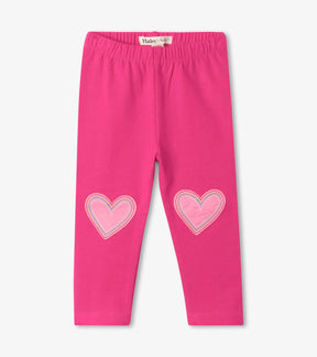 Hatley magenta baby girls leggings with white outlined heart patches at knees, front view