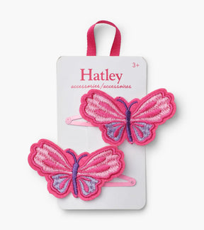Two Hatley pink embroidered butterfly hair clips with purple details and pink snap clips on a display card.