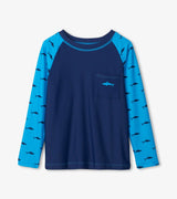 Front flat lay of Silhouette Sharks boys long sleeve rashguard with shark print sleeves and pocket