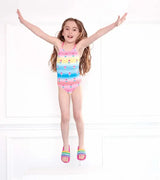 Girl jumping in Hatley Sweet Treats multicolor girls one-piece swimsuit with pastel stripes and treats print