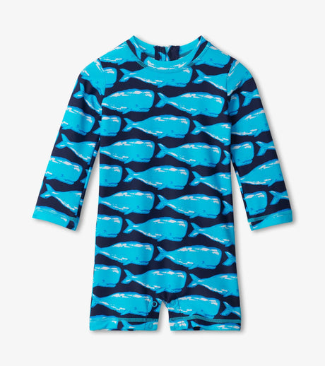 Front view of Hatley Whale Pod baby boy one-piece rashguard swimsuit in blue with allover whale print and long sleeves baby rashguard swimsuit