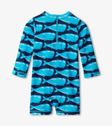 Front view of Hatley Whale Pod baby boy one-piece rashguard swimsuit in blue with allover whale print and long sleeves baby rashguard swimsuit