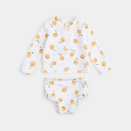 Lemon-print long-sleeve rashguard set with high-waisted swim pants laid flat, baby rashguard set on antique white background.