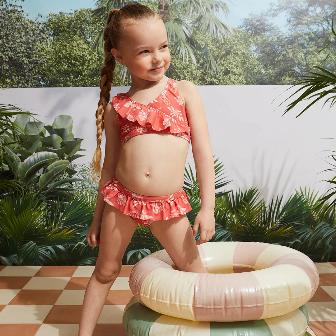 Girl wearing raspberry hibiscus kids bikini set at the pool with inflatable float.
